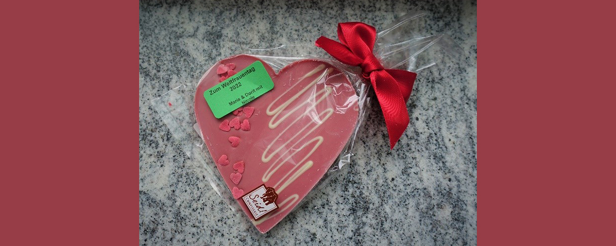 Ein in Plastik verpacktes Schokoladenherz mit Verzierung.