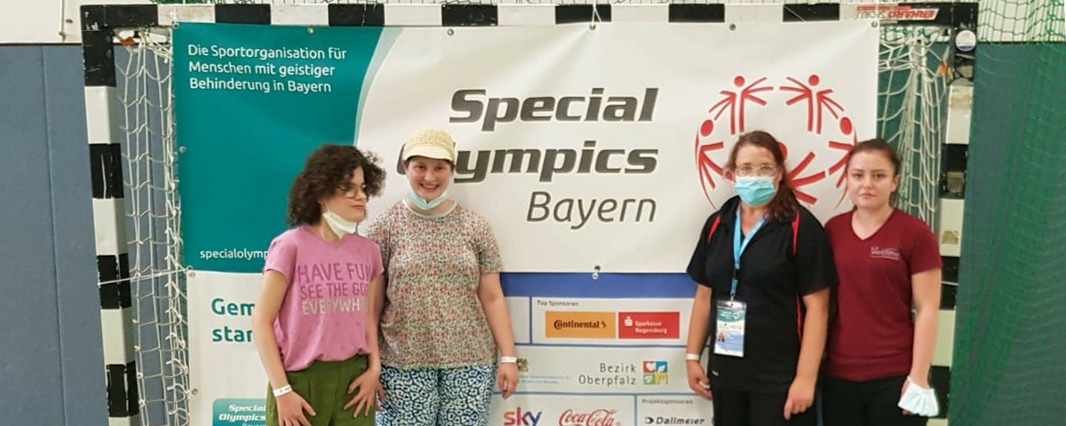 Maria Bussas und ihre Kolleginnen und Gruppenleitung stehen vor einem Special Olympics Bayern-Banner.