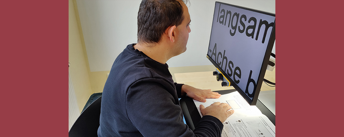 Muhammed liest einen Text in einem Heft mithilfe des Lesegeräts.