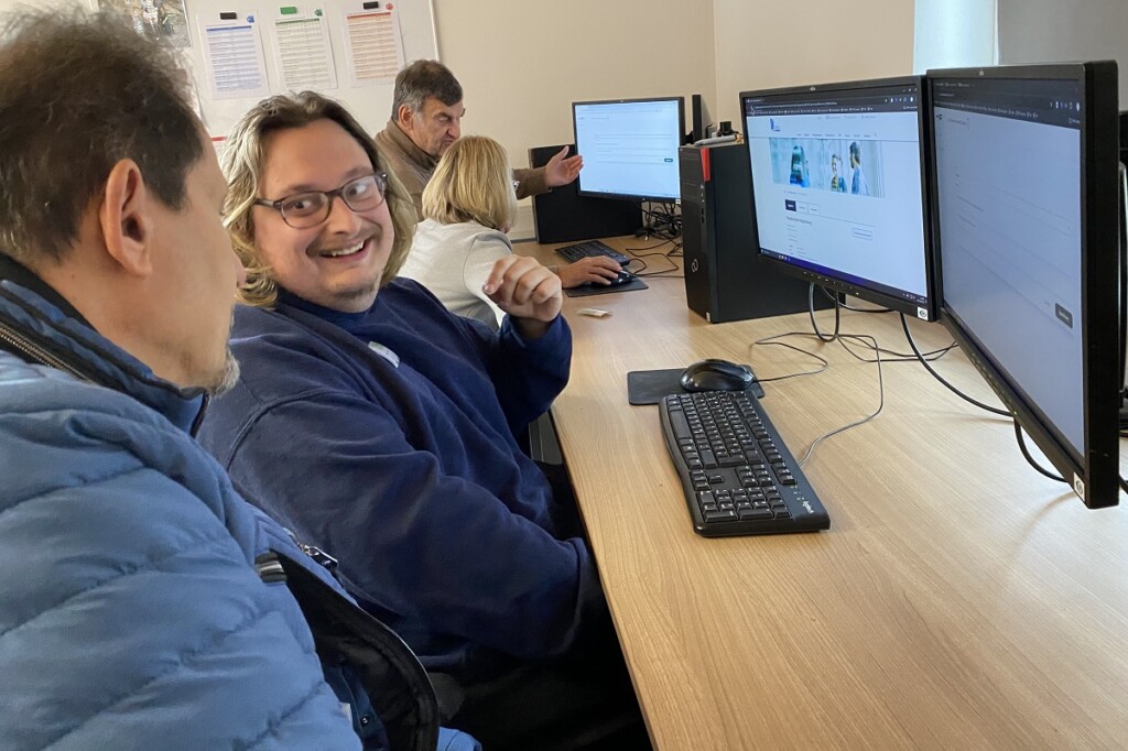 Ein Mitarbeiter der Werkstätte und ein Mitarbeiter des Hauptzollamts schauen sich gemeinsam die Webseite des Hauptzollamts an.