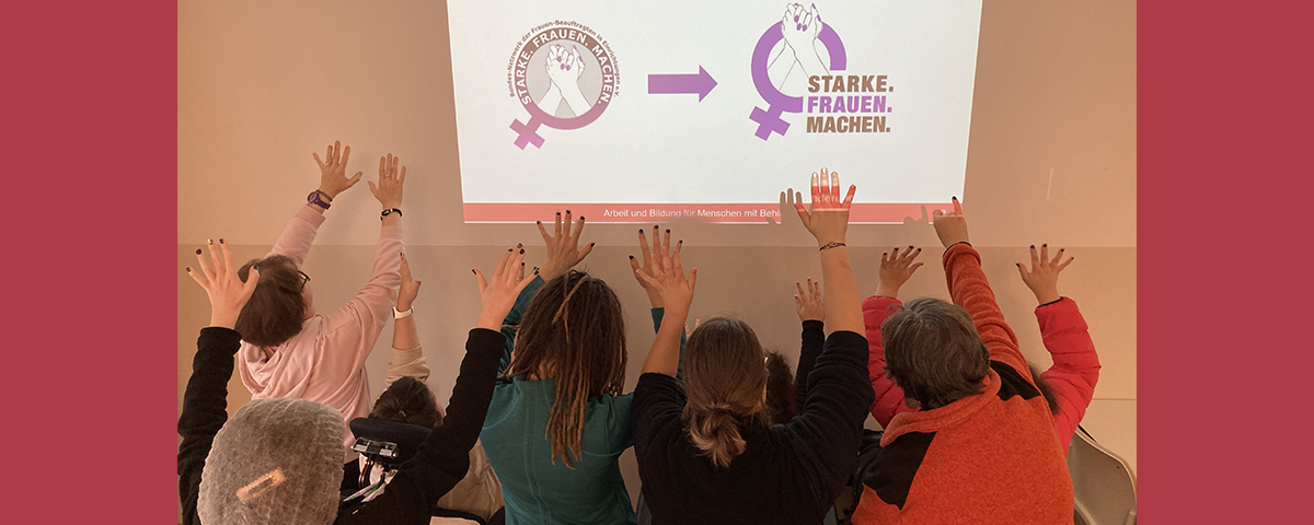 Frauen strecken Hände mit lila Fingernägeln Richtung neues Logo der Frauenbeauftragten BAG
