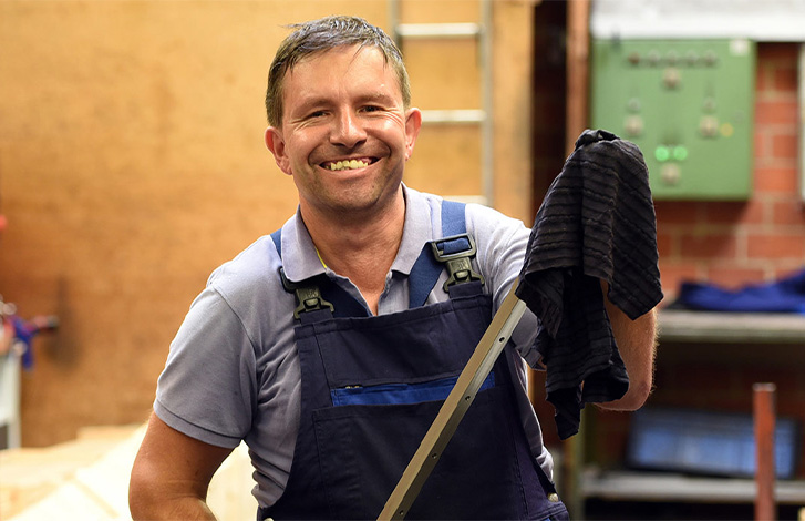 Mitarbeiter in der KJF Werkstatt lächelt freundlich in die Kamera