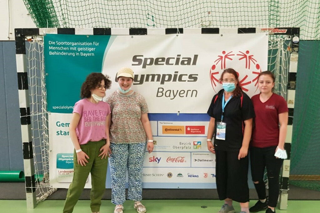Maria Bussas und ihre Kolleginnen und Gruppenleitung stehen vor einem Special Olympics Bayern-Banner.