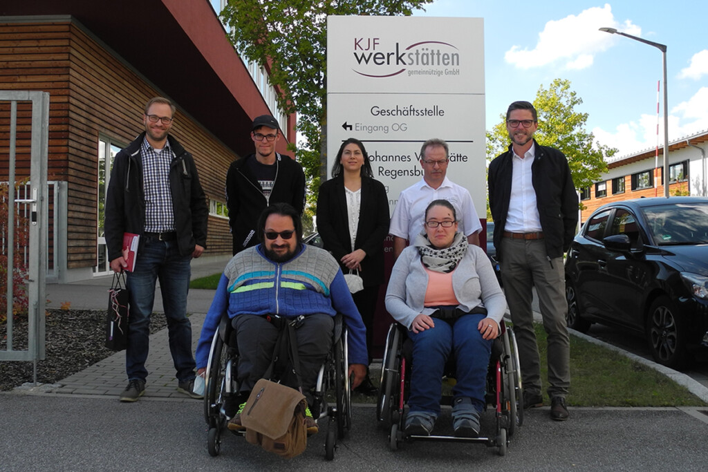 Gruppenfoto der Schichtwechselteilnehmer vor dem Schild der St. Johannes Werkstätte.