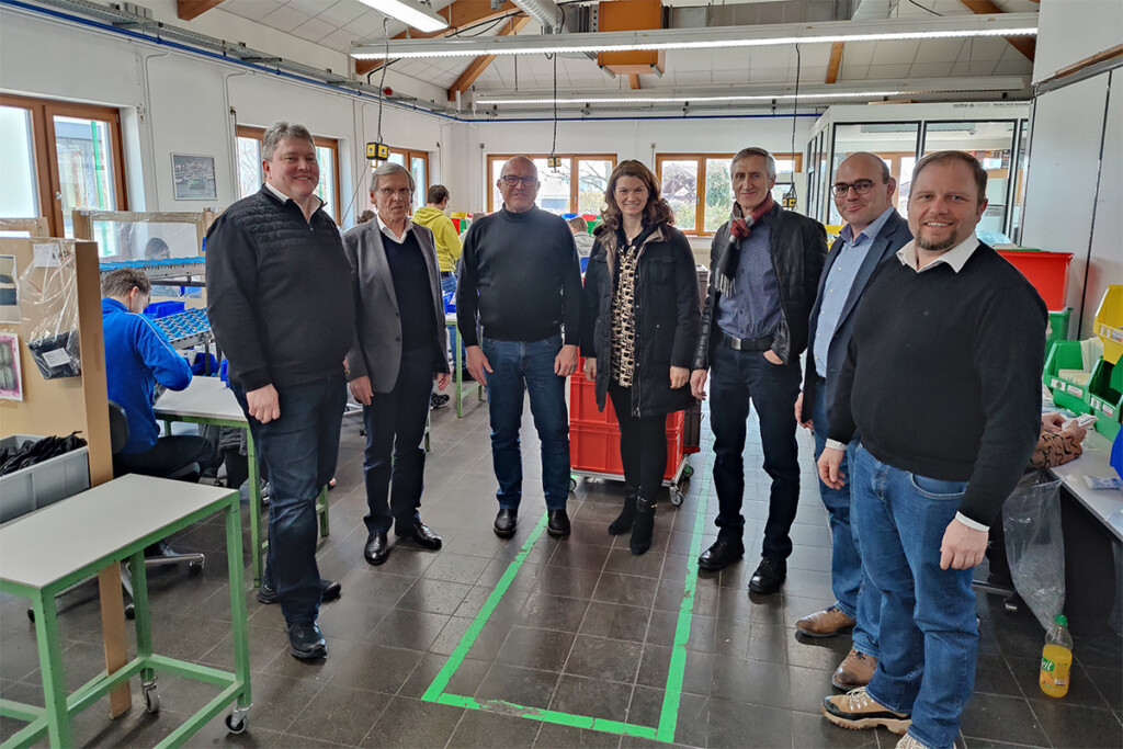 Die Politiker der Freien Wähler stehen zusammen mit Herrn Dr. Kick in einem Produktionsraum.