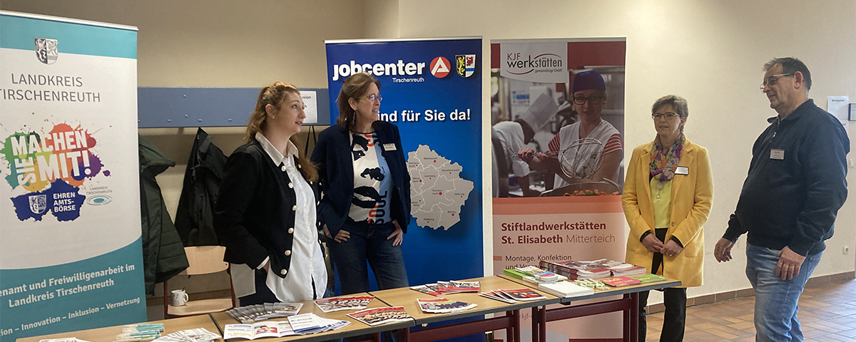 4 Personen stehen an einem Stand mit verschiedenen Flyern und Broschüren.