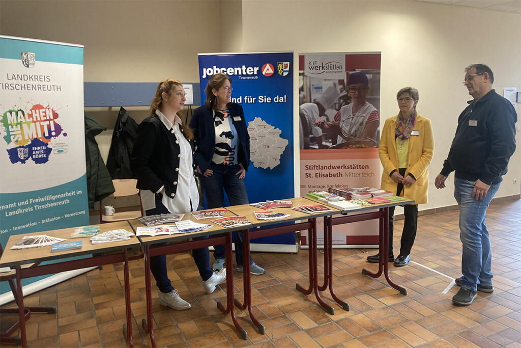 4 Personen stehen an einem Stand mit verschiedenen Flyern und Broschüren