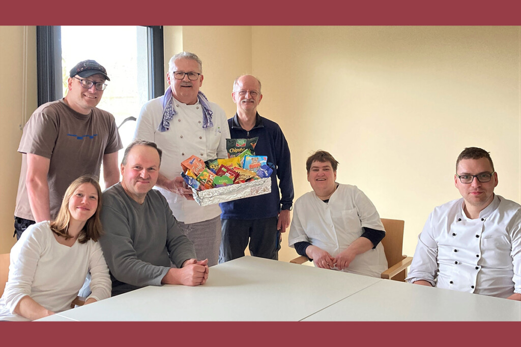 Der Werkstattrat überreicht dem scheidenden Küchenchef einen Korb mit Süßigkeiten.