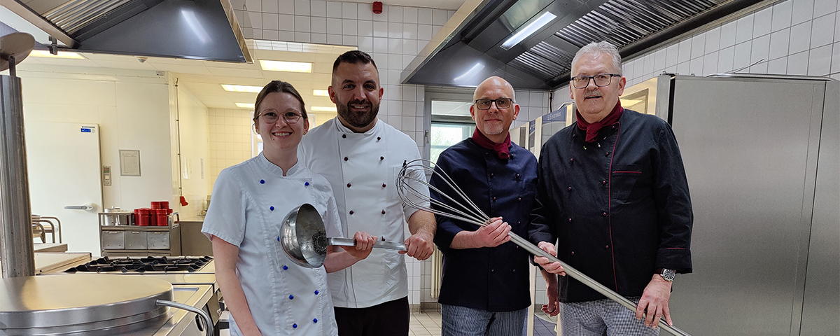 Das Küchenteam übergibt symbolisch die Kelle in der Küche.