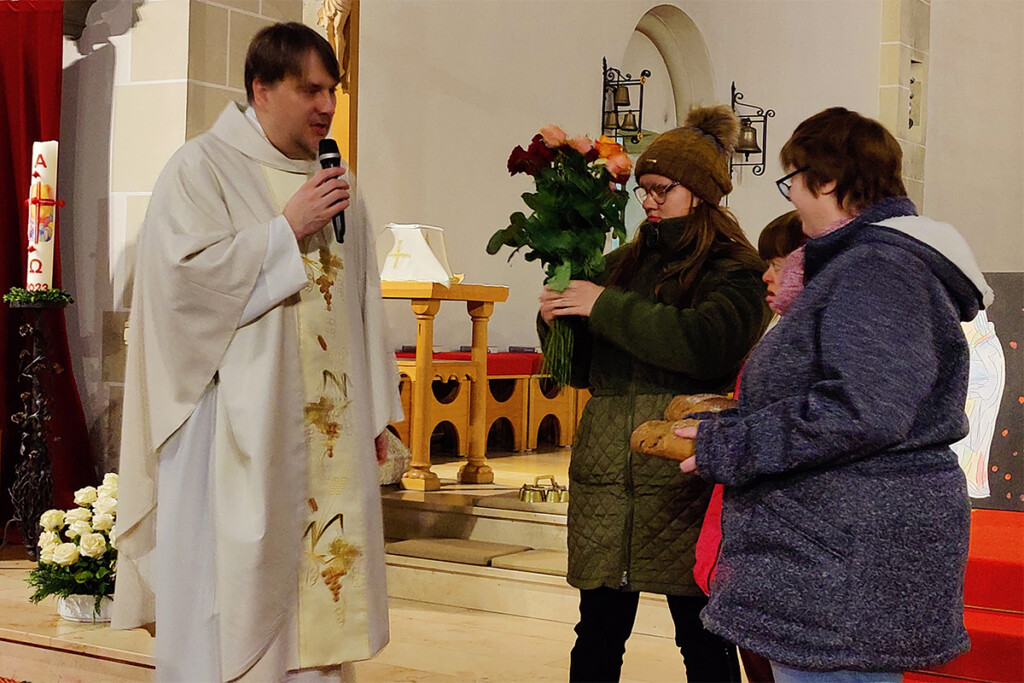 Während des Gottesdienstes zeigen Mitarbeiterinnen der Werkstätte einen Rosenstrauß und Brot.