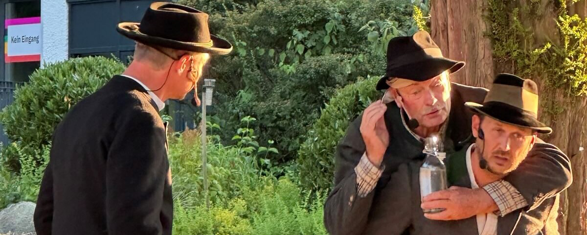 Szene aus dem Theaterstück Der Brandner Kaspar und das ewig Leben. Ein Schauspieler trägt den anderen Huckepack.