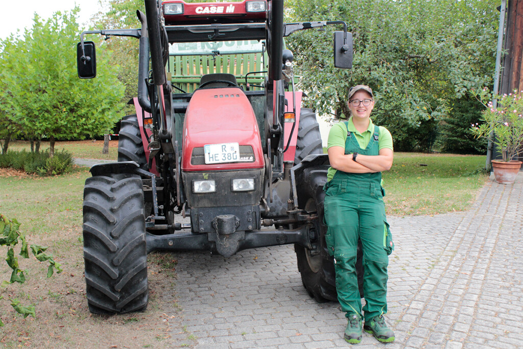 Sabrina Kiesl steht neben einen Traktor und schaut in die Kamera
