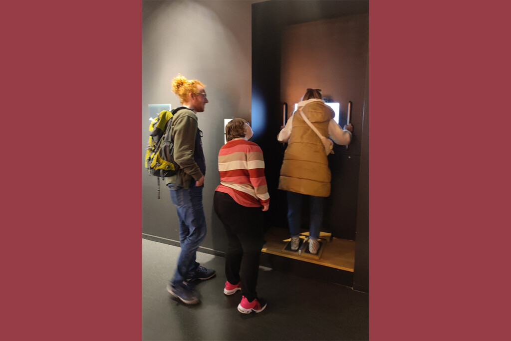 Drei Personen betrachten Exponat im Museum