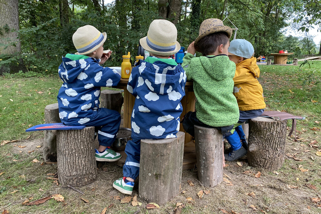 Vier Kinder sitzen am Tisch und machen Brotzeit