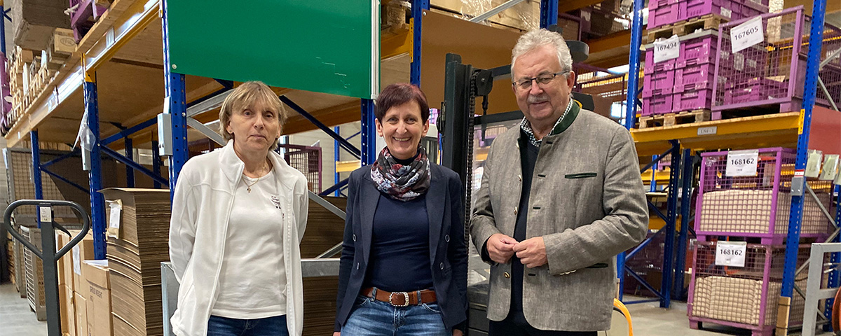 Werkstatträtin Erika Stelzl, KJF Werkstätten Geschäftsführerin Evi Feldmeier und Landrat Josef Laumer stehen im Lager und machen gemeinsam ein Bild