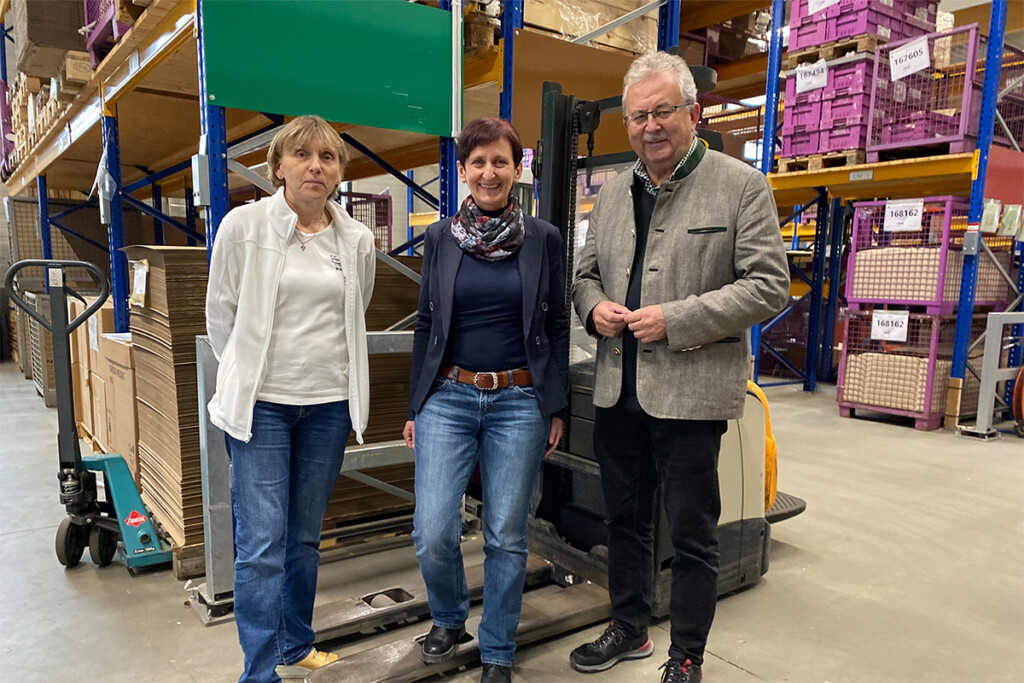 Werkstatträtin Erika Stelzl, KJF Werkstätten Geschäftsführerin Evi Feldmeier und Landrat Josef Laumer stehen im Lager und machen gemeinsam ein Bild