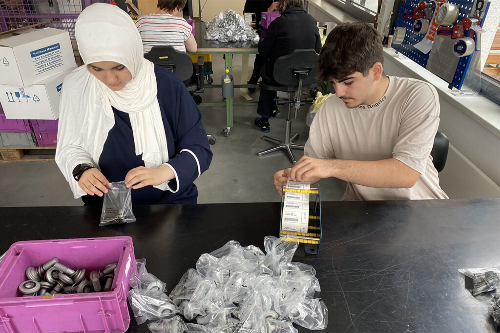 Zwei Schüler verpacken Schrauben in der Abteilung Montage der Bruder Konrad Werkstätte.