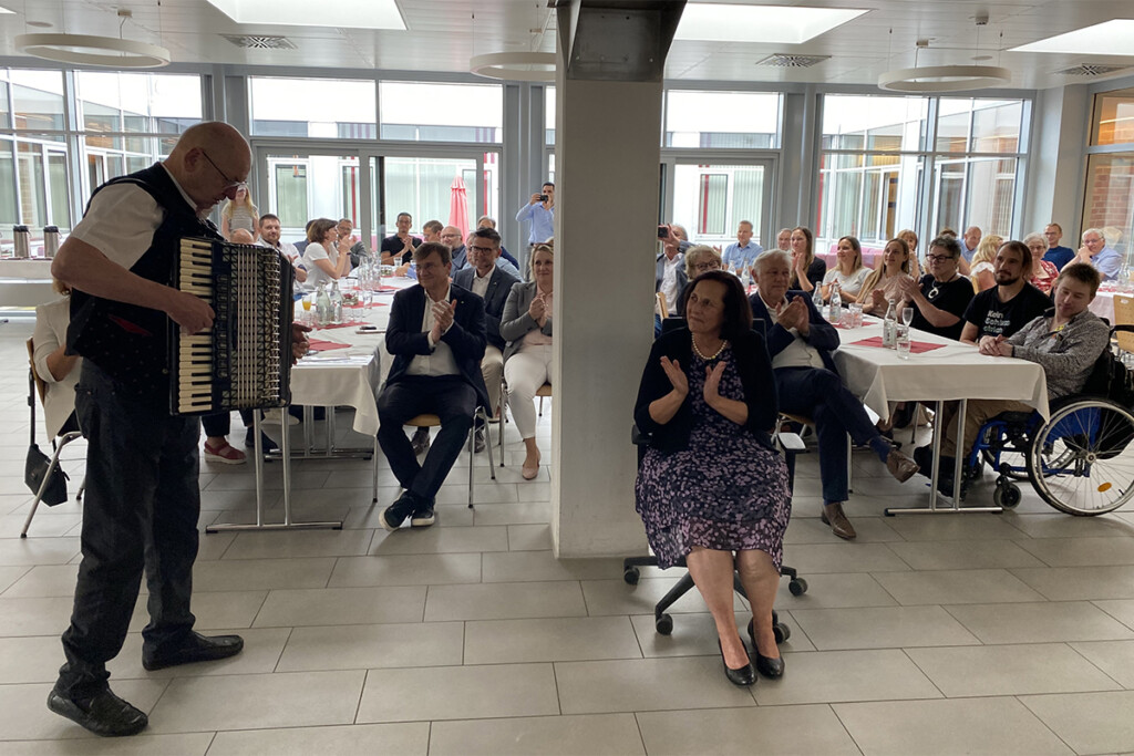 Ein Musikant mit Akkordeon spielt für Ingrid Schultes und die vielen Gäste.
