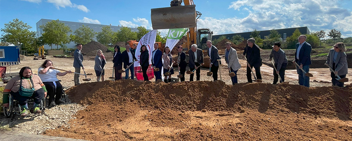 Die Gäste und Werkstätten-Mitarbeiter vollziehen den symbolischen Spatenstich.