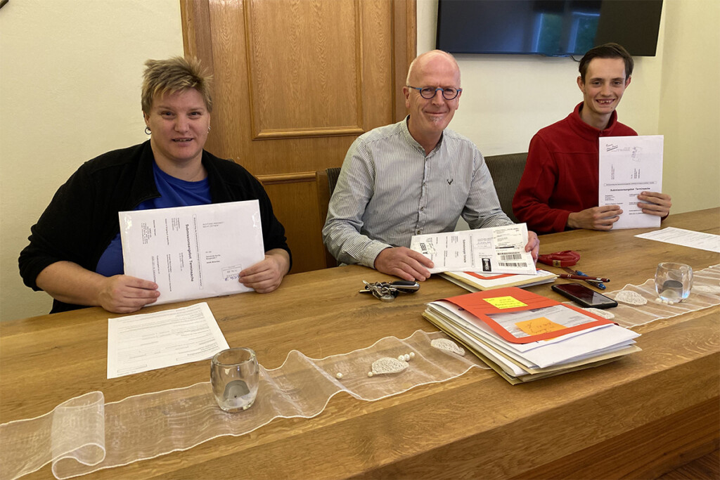 Ken-Roy Hummel (rechts) und Verena Klein (links) halten Dokumente in die Kamera.