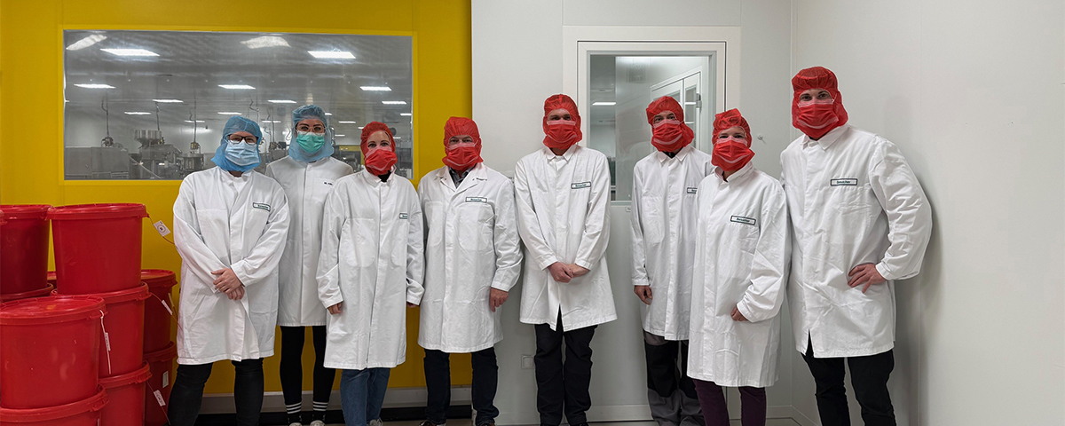 Die Gruppe aus den KJF Werkstätten steht im Produktionsbereich der Firma Vital Products. Alle tragen aus Hygienegründen Schutzkleidung.