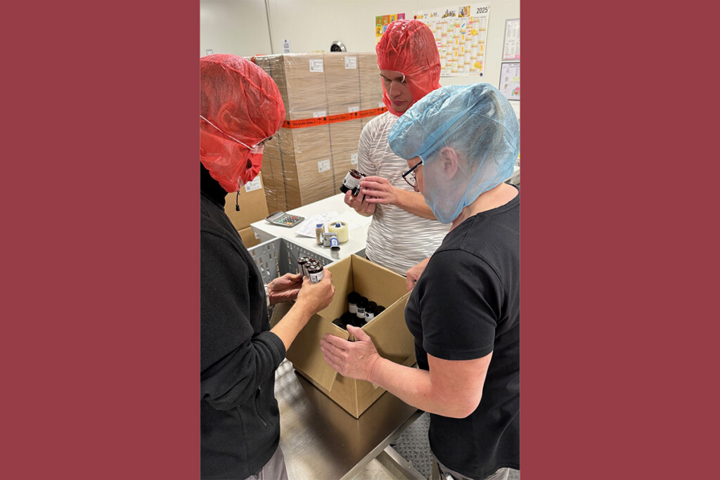 Die Mitarbeiter der KJF Werkstätten arbeiten verpacken Nahrungsergänzungsmittel. Sie tragen Schutzkleidung.