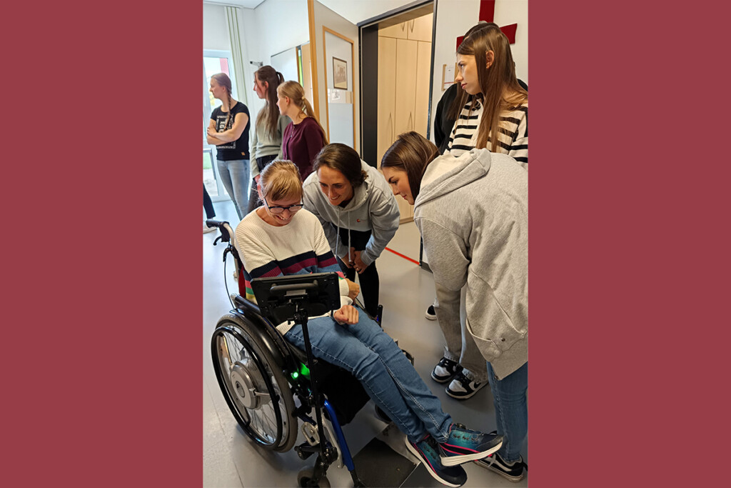 Eine Mitarbeiterin der Werkstätten zeigt zwei Auszubildenden etwas auf einem Tablet.