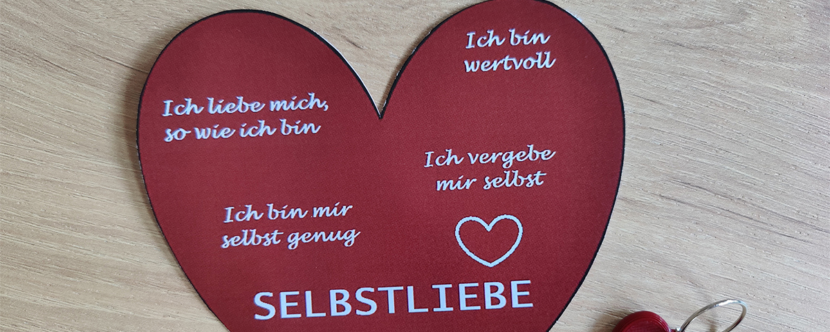 Das Bild zeigt ein großes Papierherz mit einem kleinem Schlüsselanhänger