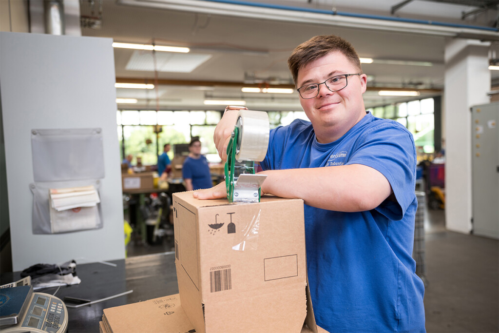 Ein Mitarbeiter mit Behinderung mit einem Päckchen