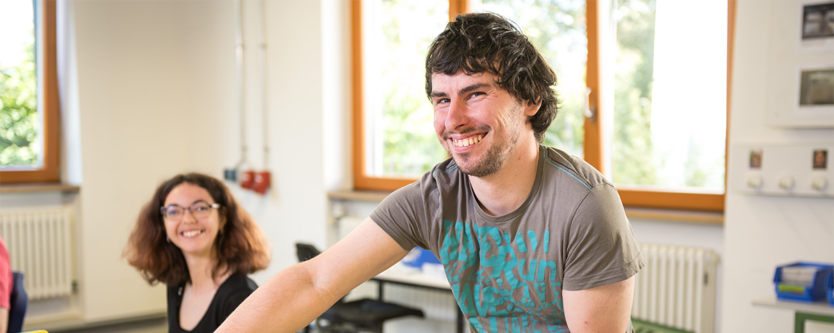 Johannes Schmid und im Hintergrund Franziska Winkler lächeln in die Kamera.