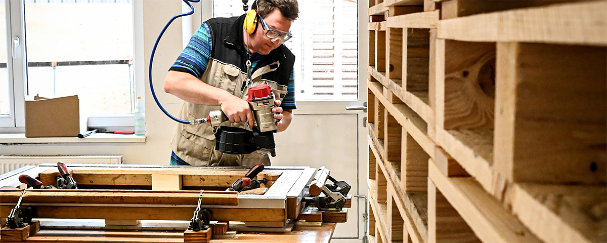 Mitarbeiter Schreinerei bedient eine Maschine