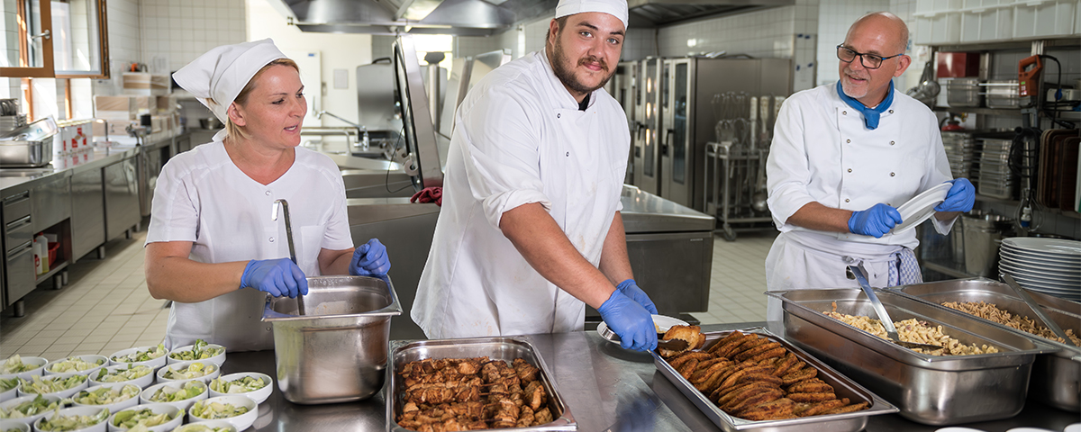 Drei Mitarbeitende bei der Essensausgabe