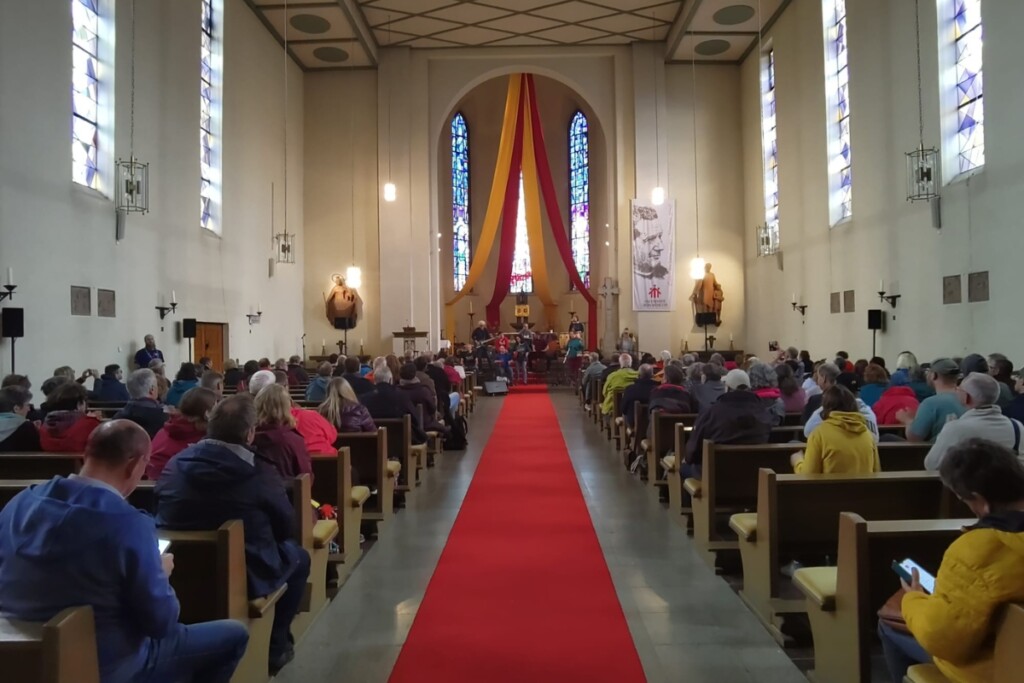 The Inclusions treten beim Katholikentag in Würzburg in einer Kirche auf, Blick durch den Mittelgang auf die Bühne und das Publikum
