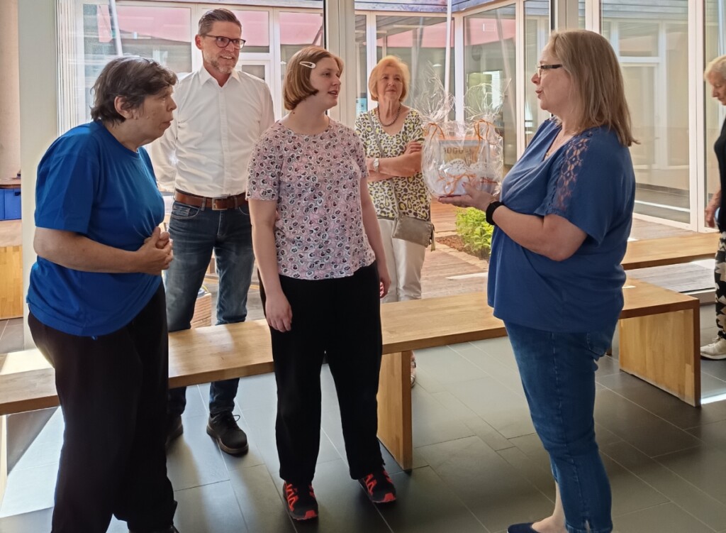 Spendenübergabe in der St. Johannes Werkstätte: Martina Stich überreicht ein Geschenk an Constanze Pöllinger und Monika Staudacher; im Hintergrund steht Standortleiter Holger Lauer mit weiteren Anwesenden