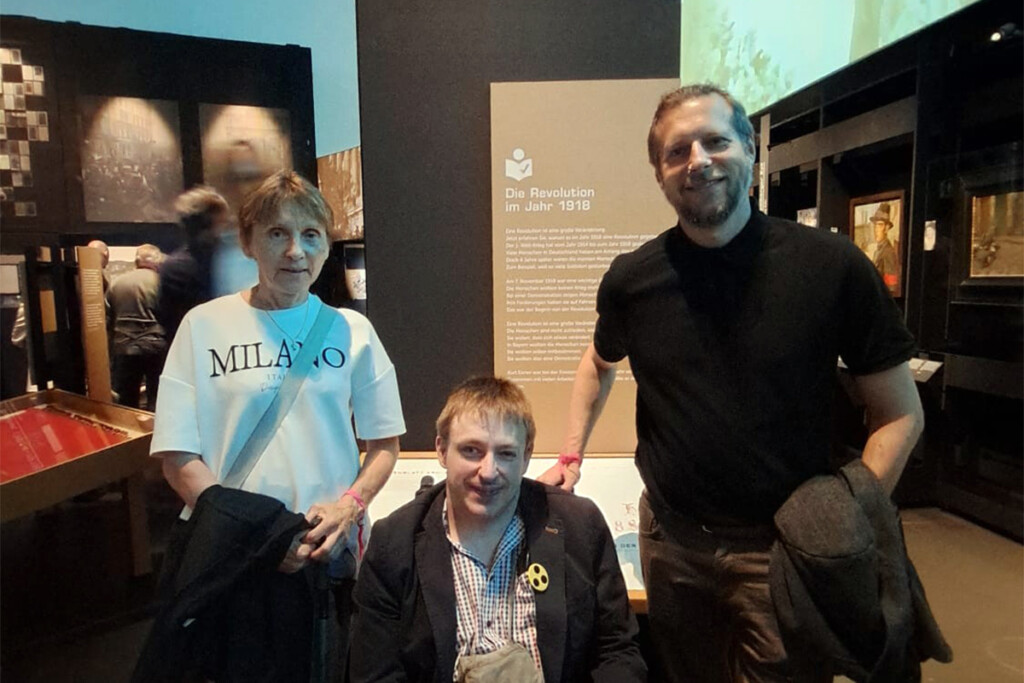 Erika Stelzl, Sebastian Müller, und Mario Franz vor der Ausstellungstafel „Die Revolution im Jahr 1918".